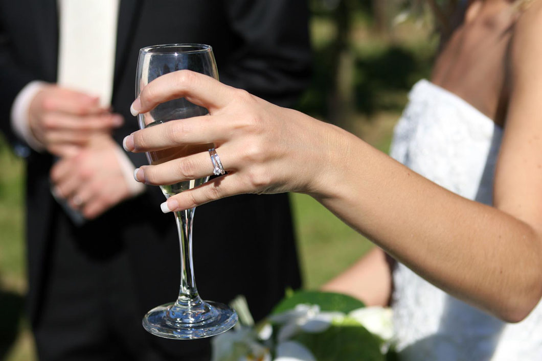 Lady in a white dress holds a glass at a function